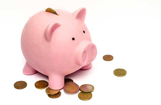 Petite banque en forme de cochon rose avec monnaie éparpillée autour